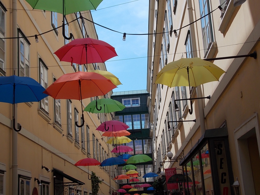 Wien Sünnhof eine alte Passage und in der Luft hängen uni farbene Regenschirme.